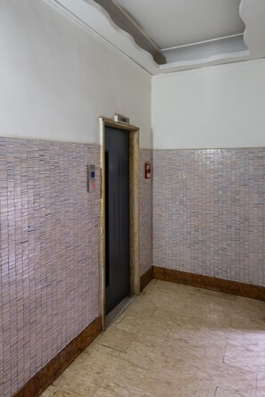 A hallway with tiled walls, a door, and a fire alarm. - Colli Aminei Vista Golfo (Naples)