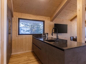 A modern kitchen with wooden walls, a large window, and a black countertop. - Superior Chalet # 2 With Sauna & Hot Tub (Stadl-Predlitz)