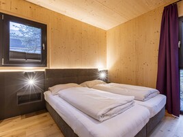 Una habitación con una cama, una ventana con persianas, un cabecero y una lámpara fijada a la pared.