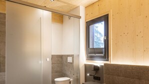 Une chambre à coucher comprenant un lit, une table de chevet, une fenêtre et une salle de bain avec des toilettes et une douche.