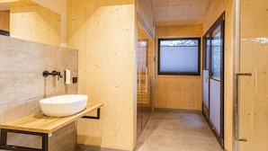 Une salle de bain moderne avec un intérieur en bois, un lavabo blanc et une cabine de douche en verre.