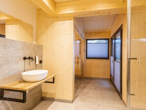 A modern bathroom with a wooden interior, a white sink, and a glass shower enclosure.