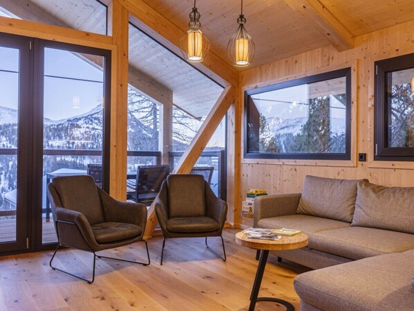 A cozy interior with wooden walls, large windows, and a sofa. - Superior Chalet # 2 With Sauna & Hot Tub (Stadl-Predlitz)