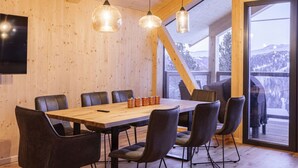 Un espace de restauration moderne avec une table et des chaises en bois, de grandes fenêtres et une vue sur un paysage enneigé.