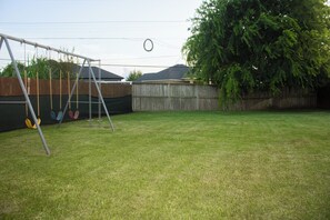 A backyard with a swing set and a wooden fence.