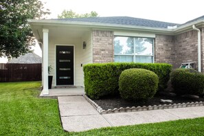 A residential house with a front porch, a black door, and a brick facade.