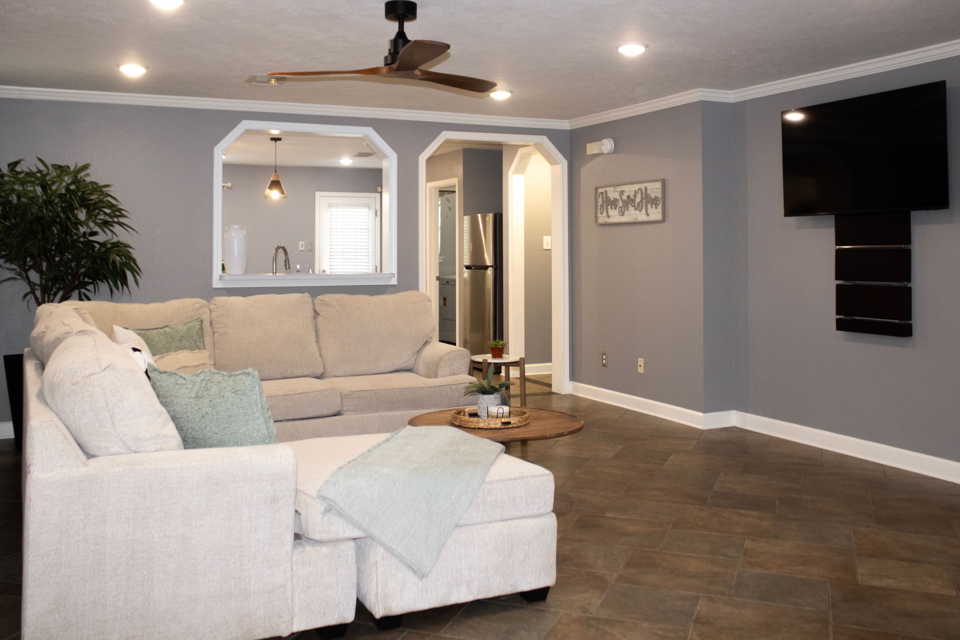 A living room with a sofa, a coffee table, a TV, and a ceiling fan.