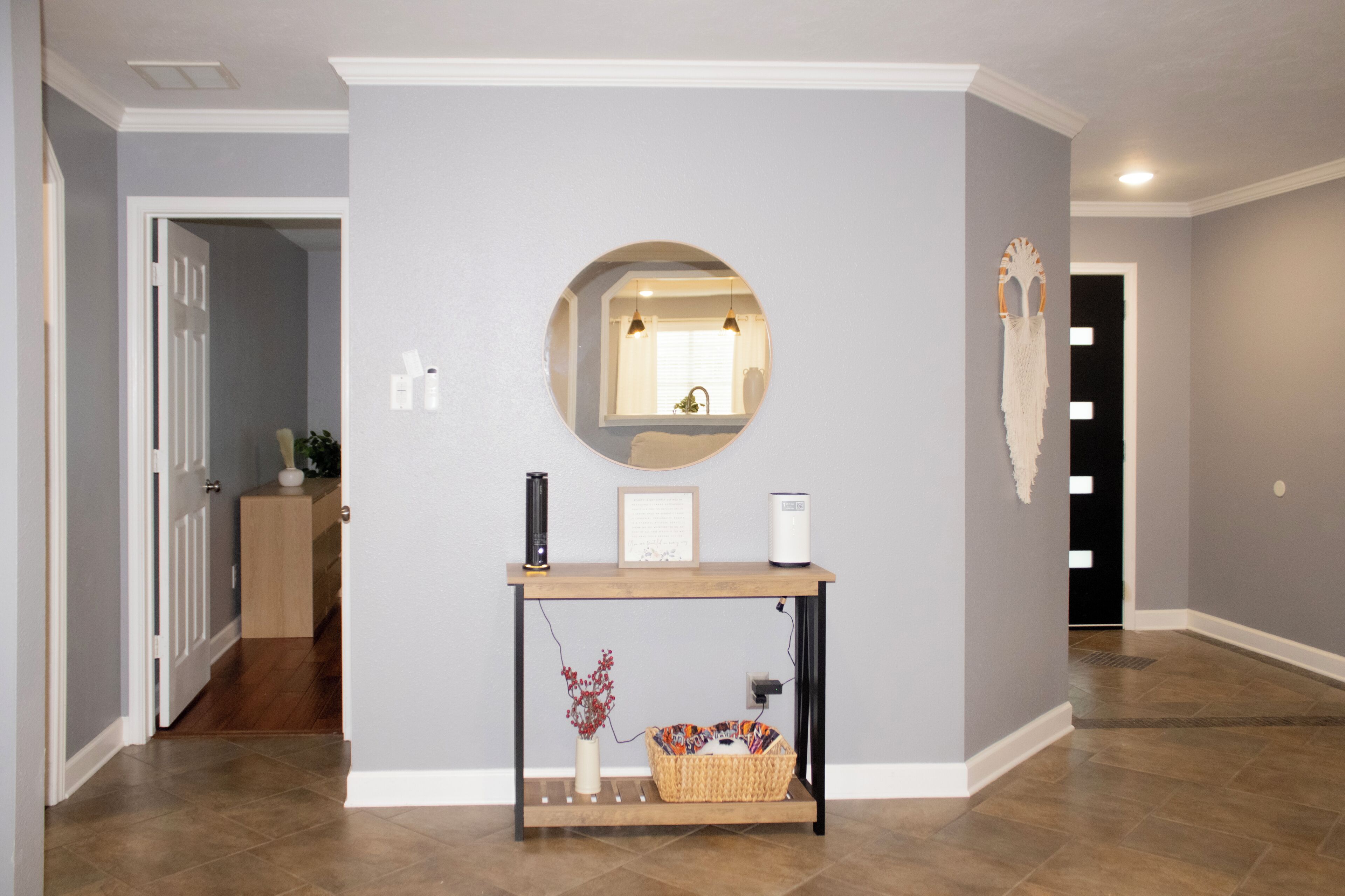Un couloir avec une console, un miroir et une porte.