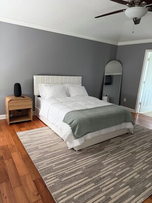 A bedroom with a bed, a nightstand, a ceiling fan, and a large mirror. - Your home away from home at Casa Palapa (Missouri City)