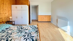 A bedroom with a bed, wardrobe, bedside table, lamp, and a hanging light fixture. - 'Le Belle Vue' Apartment: Mountain View, Shared Garden & Wi-Fi (Villard-de-Lans)
