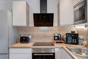 Uma cozinha moderna com forno embutido, máquina de café e micro-ondas.