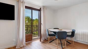 A room with a dining table, chairs, a TV mounted on the wall, and a sliding glass door leading to an outdoor area.