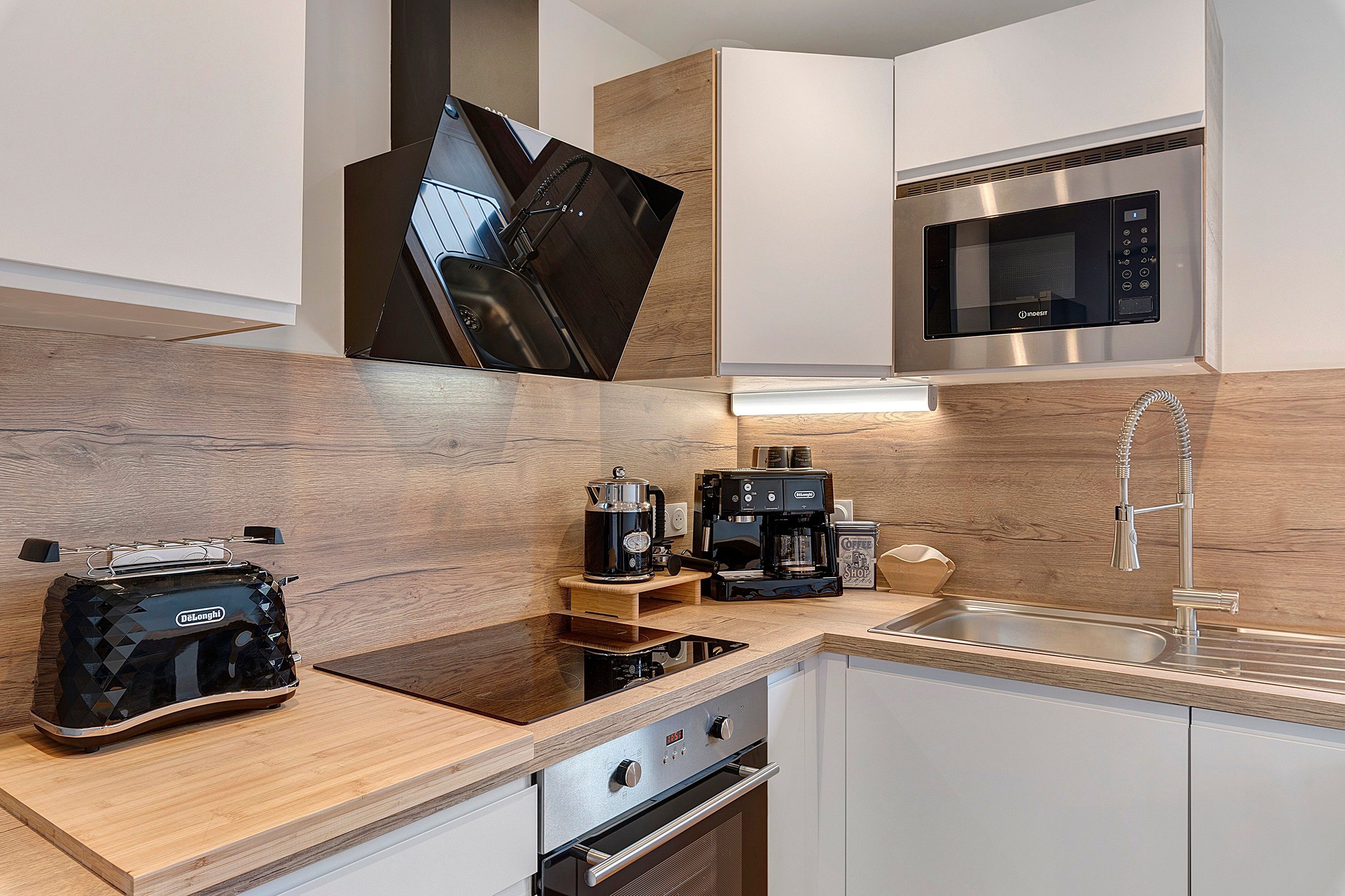 Una cocina moderna con horno integrado, cafetera y lavamanos.