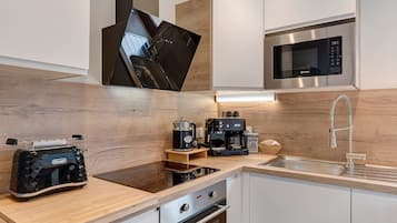 Una cocina moderna con horno integrado, cafetera y lavamanos.