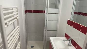 Un baño con ducha, lavamanos y espejo.