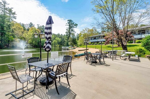 An outdoor patio area with tables and chairs, a fountain, and a sign indicating no swimming in the lake.
