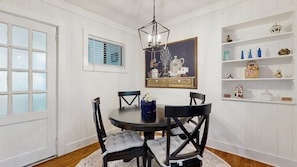 Une salle à manger avec une table ronde, des chaises noires, un lustre et des murs recouverts de panneaux blancs.