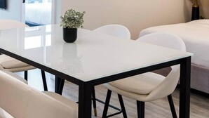 A modern dining area with a glass table, black metal chairs, and a unique ceiling light fixture. - Modern Condo Getaway with Free Parking (Toronto)