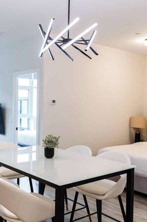 Een moderne eethoek met een glazen tafel, zwarte metalen stoelen en een bijzondere hanglamp.