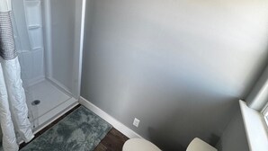 A bathroom with a shower, toilet, and a rug on the floor. - Tranquil 1-bedroom bungalow with AC in Bolivar Peninsula (Bolivar Peninsula)