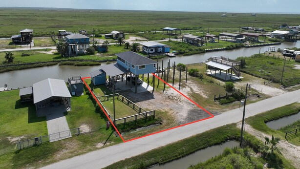 An aerial view of a coastal property with multiple buildings, a dock, and a waterway. - Tranquil 1-bedroom bungalow with AC in Bolivar Peninsula (Bolivar Peninsula)