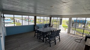 A covered outdoor area with a table and chairs, large windows, and a view of the surrounding landscape. - Tranquil 1-bedroom bungalow with AC in Bolivar Peninsula (Bolivar Peninsula)