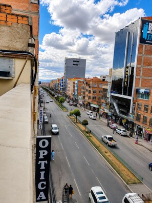 A street view with a hotel building, a sign for 'OPTICA', and a clear sky.