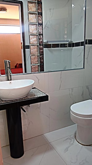 Un baño con un lavamanos blanco, un inodoro y un espejo con marco decorativo.