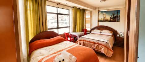 Een hotelkamer met twee bedden, een raam met gordijnen, een schilderij aan de muur en een nachtkastje met een lamp.