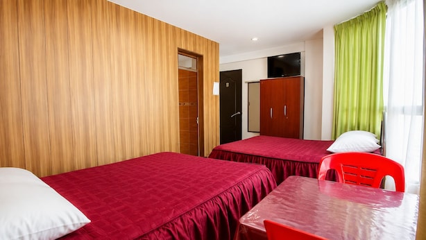 Una habitación con dos camas, una mesa y sillas.