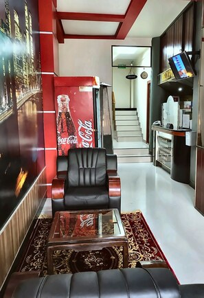 Una sala de estar moderna con un sofá, una mesa de centro de vidrio, un refrigerador rojo Coca-Cola y una escalera que lleva a otro nivel.
