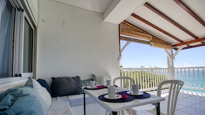 Un balcone con un tavolo apparecchiato per due persone, un divano e vista sul mare.