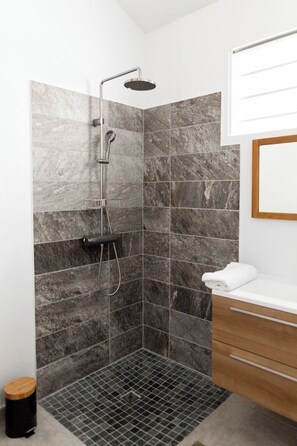 A modern bathroom with a shower, tiled walls, a wooden vanity, and a white sink. - At Alexandra's, AZUR Apartment (Le Diamant)