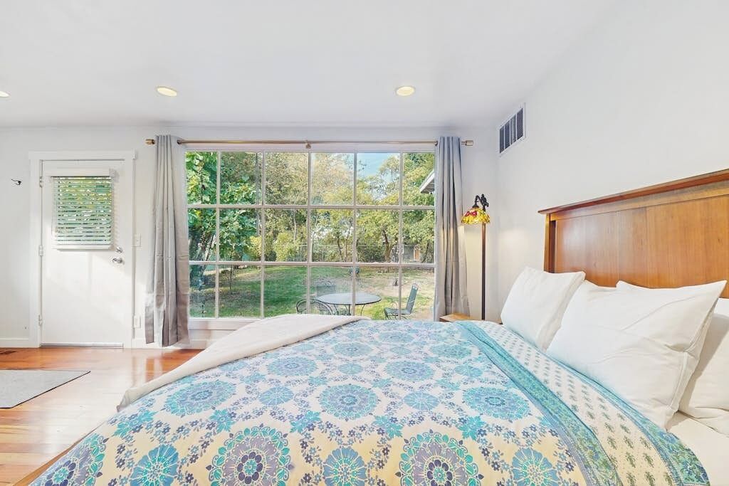 Un dormitorio con una cama grande, vistas al exterior a través de un ventanal corredero y un cabecero de madera.