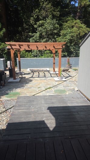 A wooden deck with a pergola structure, stone flooring, and a potted plant. - Fully Remodeled and Updated, just 90-mins from San Francisco! (Monte Rio)