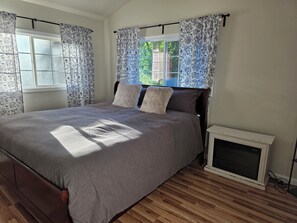 A bedroom with a bed, curtains, a radiator, and a window. - Fully Remodeled and Updated, just 90-mins from San Francisco! (Monte Rio)