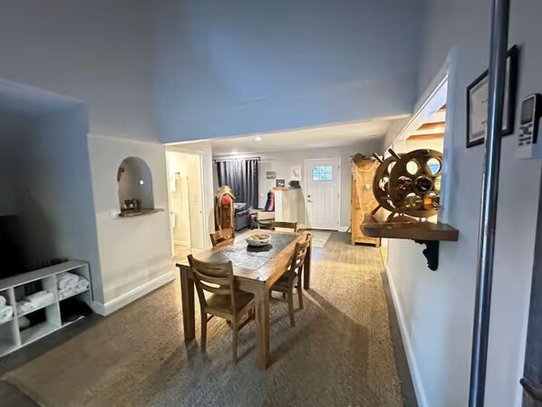 A dining area with a wooden table and chairs, a television on the left, and a wall-mounted shelf with bottles. - Fully Remodeled and Updated, just 90-mins from San Francisco! (Monte Rio)