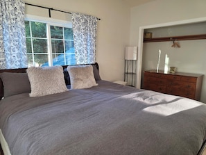 A bedroom with a bed, a dresser, a nightstand, and a window with curtains. - Fully Remodeled and Updated, just 90-mins from San Francisco! (Monte Rio)
