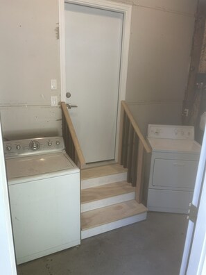 A laundry area with a washing machine, dryer, and wooden stairs leading to a door. - Fully Remodeled and Updated, just 90-mins from San Francisco! (Monte Rio)