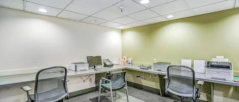 Una sala de conferencias con una larga mesa, dos sillas, una computadora e impresora.