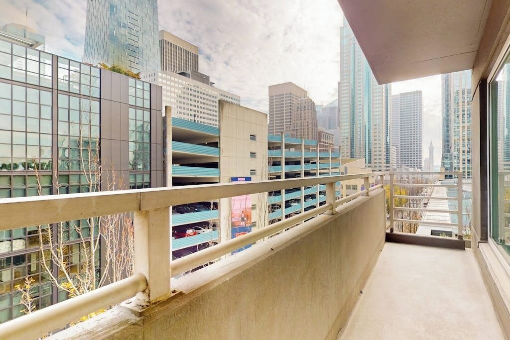 A balcony with a view of high-rise buildings and a parking garage.