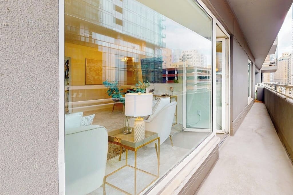 A modern interior with a glass partition, a dining area with a table and chairs, and a view of the cityscape.