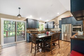 A modern kitchen with dark cabinetry, stainless steel appliances, and a dining area with wooden chairs. - Welcoming 2BR Lakeview - Deck - Firepit - Washer Dryer (Anderson Island)