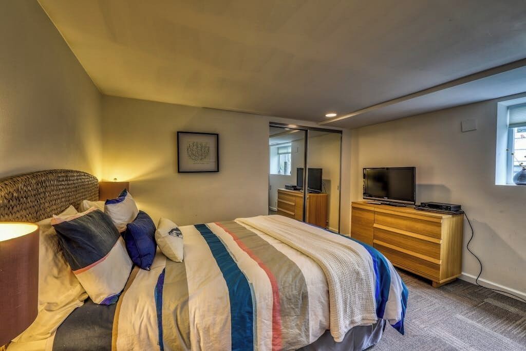 Een slaapkamer met een bed, een dressoir, een televisie en een spiegel.