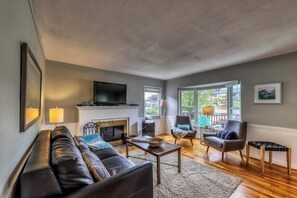 Ein Wohnzimmer mit Kamin, Ledersofa, Sesseln und Fernseher.