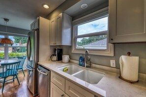 Eine moderne Küche mit Kühlschrank aus Edelstahl, einer doppelten Spüle und einem Fenster mit Blick ins Freie.