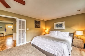 A bedroom with a large bed, a door leading to another room, a wall-mounted artwork, and a nightstand with a lamp. - Downtown 3BR - Deck - Washer Dryer (Seattle)