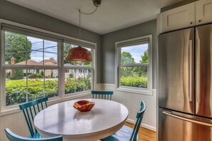 A kitchen with a round table, chairs, a hanging light fixture, and a stainless steel refrigerator. - Downtown 3BR - Deck - Washer Dryer (Seattle)
