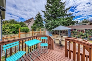 A wooden deck with a table and chairs, surrounded by a wooden fence and greenery. - Downtown 3BR - Deck - Washer Dryer (Seattle)