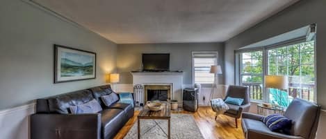 A living room with a fireplace, leather sofa, and a television.